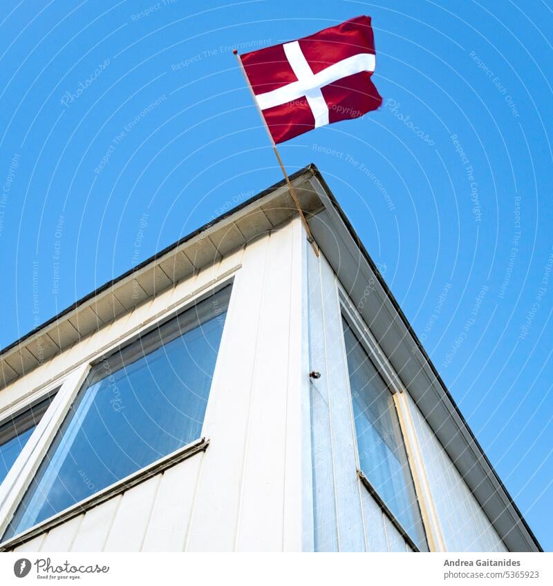 View upwards at a bathhouse at the beach of Løkken, at the top center of the picture a waving Danish flag, partial shot, square, 1:1 Bath house Changing cabine