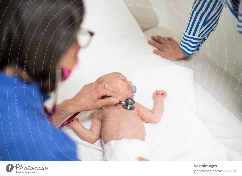 Baby lying on his back as his doctor examines him during a standard medical checkup baby infant boy pediatrician stethoscope heartbeat childhood medicine clinic