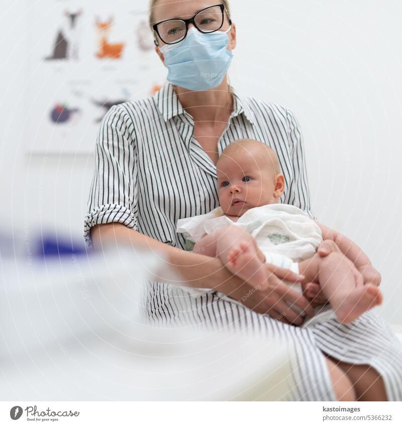 Mother holding her baby boy at medical appointment at pediatrician office. parent consultation consulting medicine stethoscope care mother child doctor visit