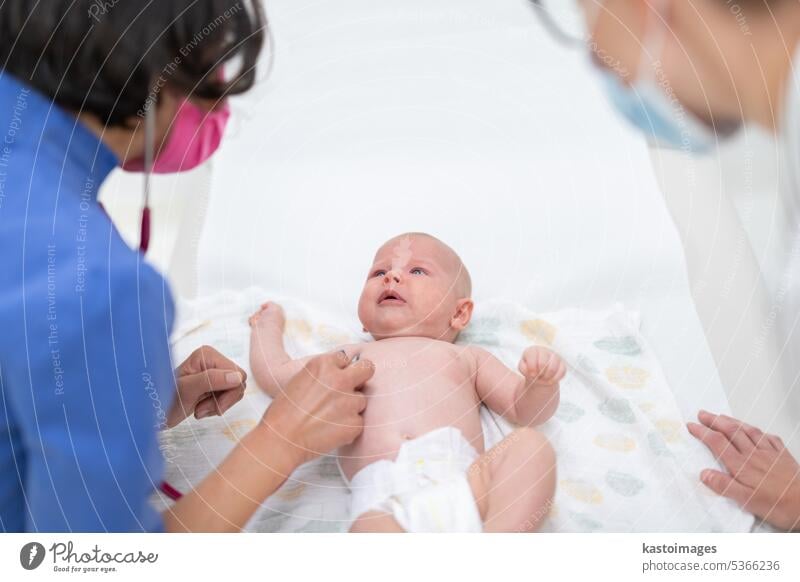 Baby lying on his back as his doctor examines him during a standard medical checkup baby infant boy pediatrician stethoscope heartbeat childhood medicine clinic