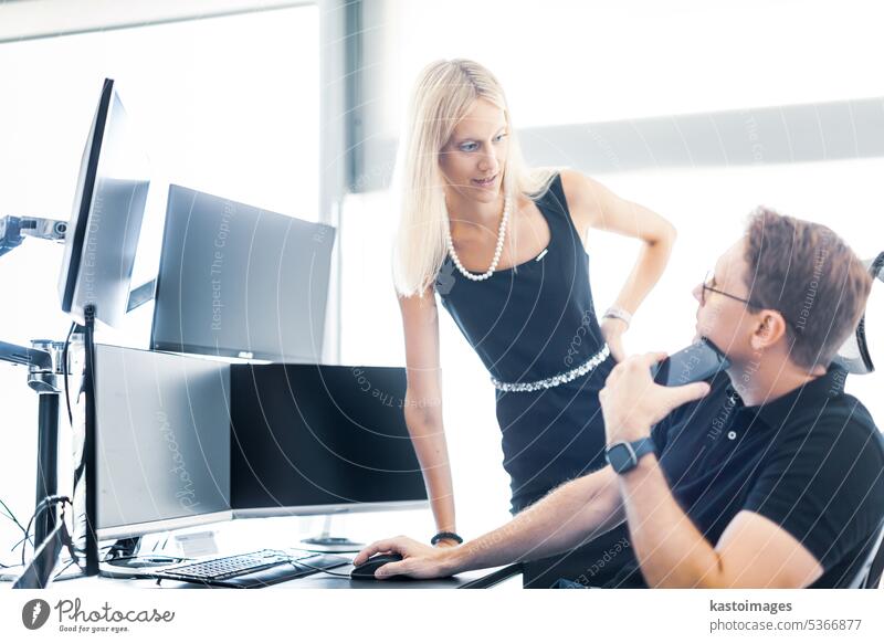 Business people looking at data on multiple computer screens, solving business issue at business meeting in modern corporate office. Business success concept.