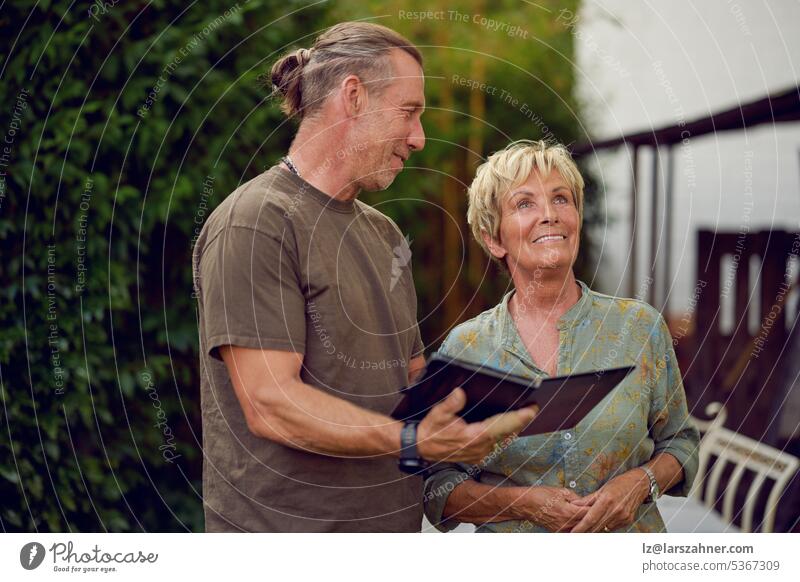 Craftsman being a gardener talking to a female senior customer holding a digital tablet making an offer craftsman woman explaining showing outside concept