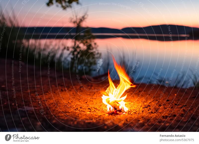 Bonfire. Small campfire with gentle flames beside a lake during a glowing sunset. San Juan night on the beach. People jumping over the bonfires. Bonfire at night.