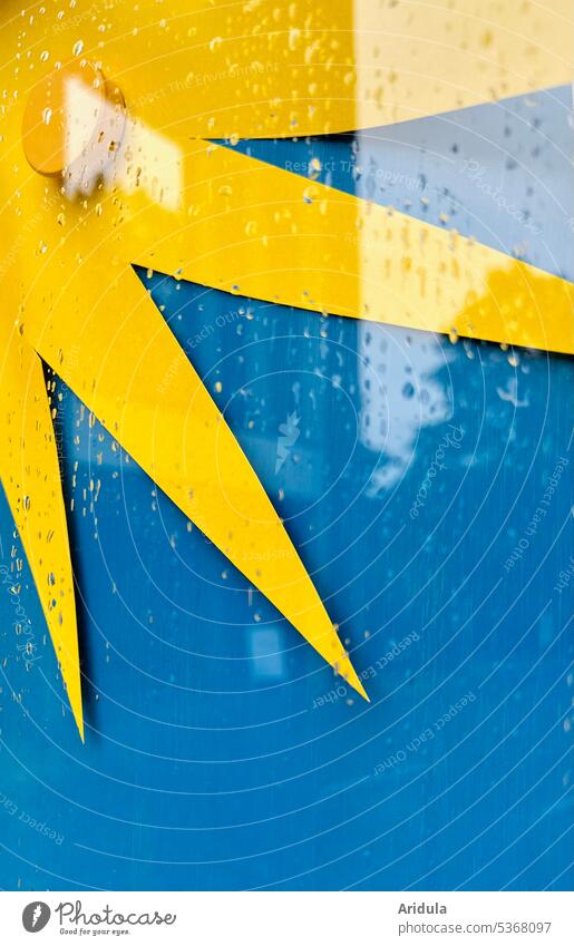 Yellow sun on blue background in showcase with raindrops Sun Blue Colored paper Glass display reflection Reflection Water Drop Wet Rain Drops of water