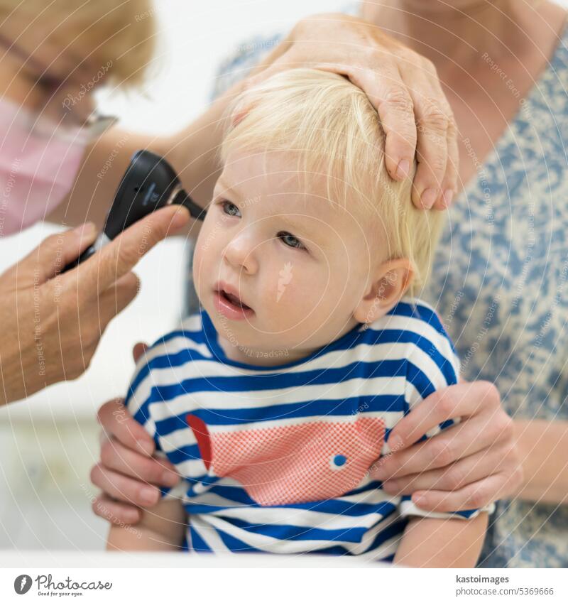 Infant baby boy child being examined by his pediatrician doctor during a standard medical checkup in presence and comfort of his mother. National public health and childs care care koncept.