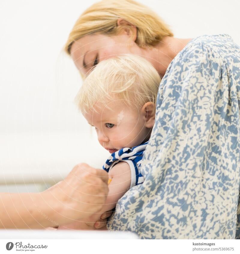 Child beeing vaccinated by pediatrician in presence of his mother. Preventive vaccination against Diphtheria, whooping cough, tetanus, hepatitis, haemophilus influenzae, pneumococcus, poliomyelitis