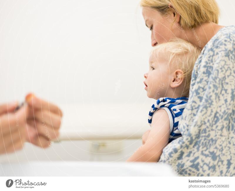 Child beeing vaccinated by pediatrician in presence of his mother. Preventive vaccination against Diphtheria, whooping cough, tetanus, hepatitis, haemophilus influenzae, pneumococcus, poliomyelitis