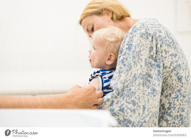 Child beeing vaccinated by pediatrician in presence of his mother. Preventive vaccination against Diphtheria, whooping cough, tetanus, hepatitis, haemophilus influenzae, pneumococcus, poliomyelitis