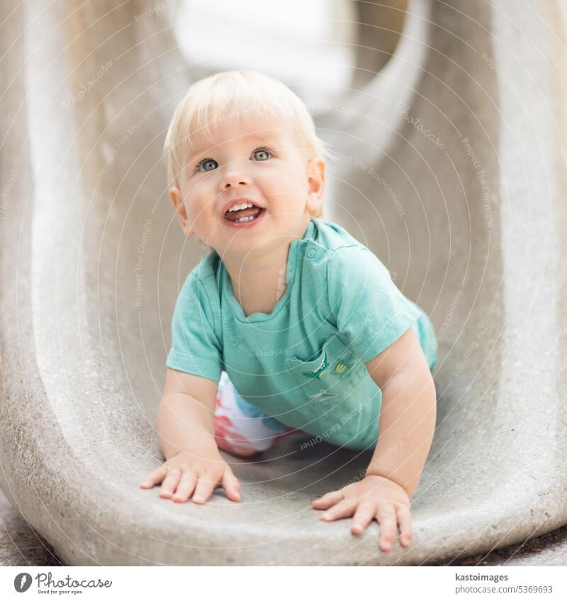 Child playing on outdoor playground. Toddler plays on school or kindergarten yard. Active kid on stone sculpured slide. Healthy summer activity for children. Little boy climbing outdoors.