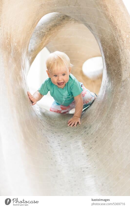 Child playing on outdoor playground. Toddler plays on school or kindergarten yard. Active kid on stone sculpured slide. Healthy summer activity for children. Little boy climbing outdoors.