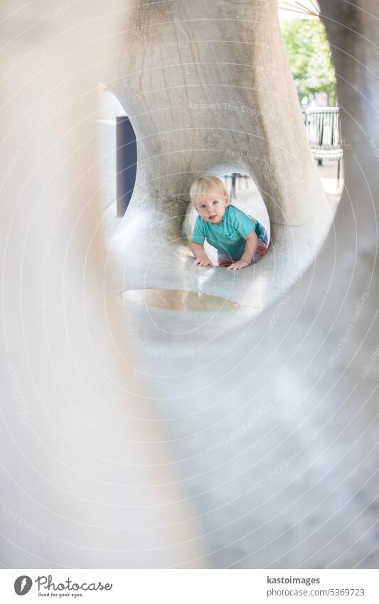 Child playing on outdoor playground. Toddler plays on school or kindergarten yard. Active kid on stone sculpured slide. Healthy summer activity for children. Little boy climbing outdoors.