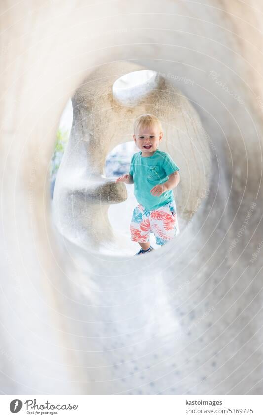 Child playing on outdoor playground. Toddler plays on school or kindergarten yard. Active kid on stone sculpured slide. Healthy summer activity for children. Little boy climbing outdoors.