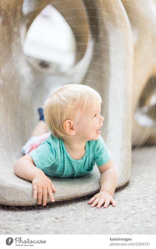 Child playing on outdoor playground. Toddler plays on school or kindergarten yard. Active kid on stone sculpured slide. Healthy summer activity for children. Little boy climbing outdoors.