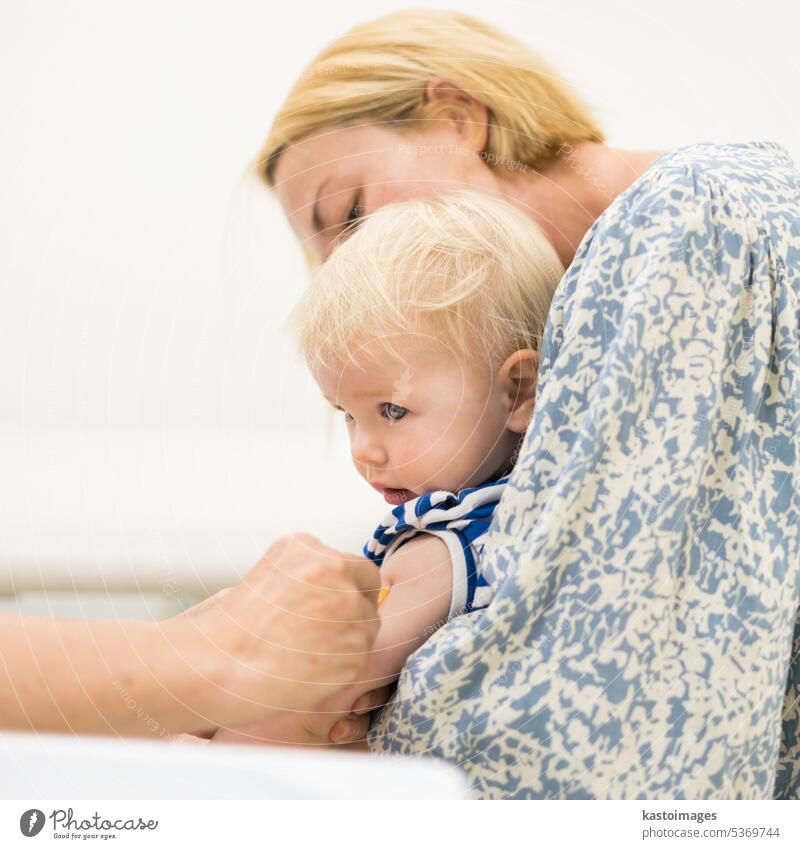 Child beeing vaccinated by pediatrician in presence of his mother. Preventive vaccination against Diphtheria, whooping cough, tetanus, hepatitis, haemophilus influenzae, pneumococcus, poliomyelitis