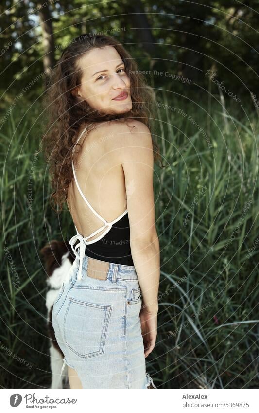 side portrait of young beautiful brunette smiling woman in front of forest warm Summery Beautiful weather plants proximity Day tranquillity Self-confident