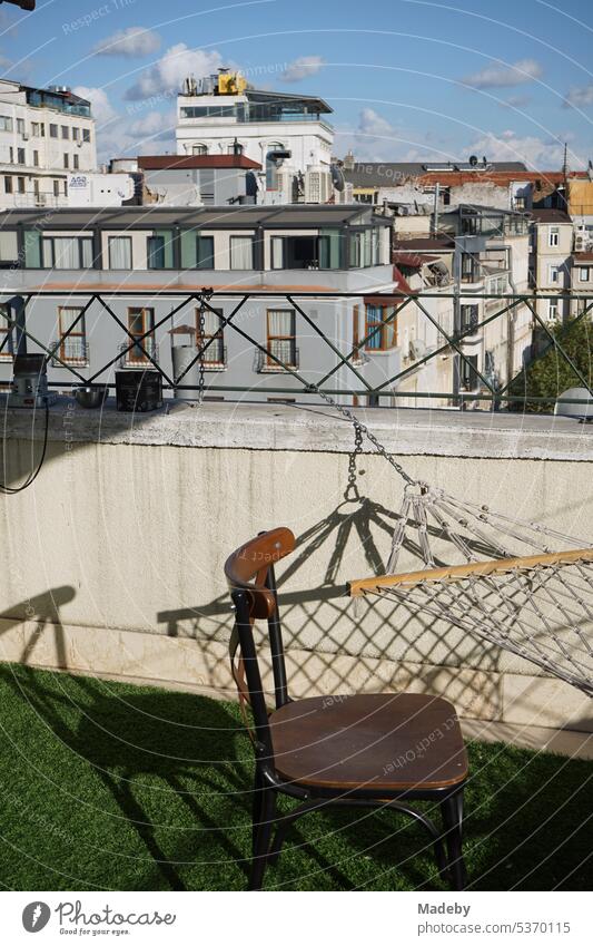 Old wooden chair, hammock and green artificial grass on the roof terrace of a hotel in Taksim district in summer sunshine on Istiklal Caddesi in Istanbul on the Bosphorus in Turkey