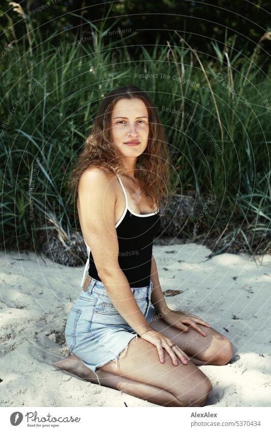 side portrait of young beautiful brunette woman kneeling in the sand in front of a forest warm Summery Beautiful weather plants proximity Day tranquillity