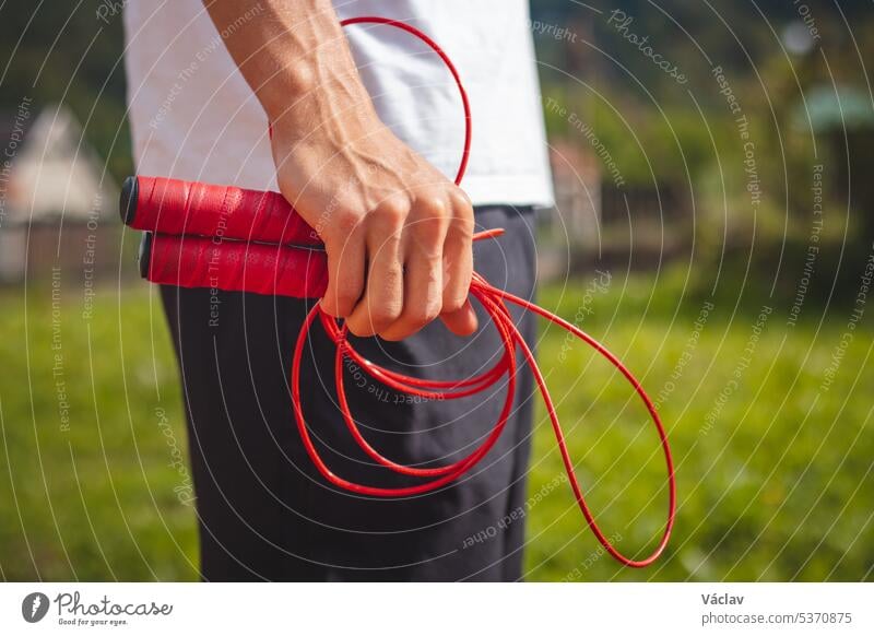 Brown-haired boy with an athletic build promotes the jump rope as one of the best tools for improving endurance, jumping power sport person sportsman practice