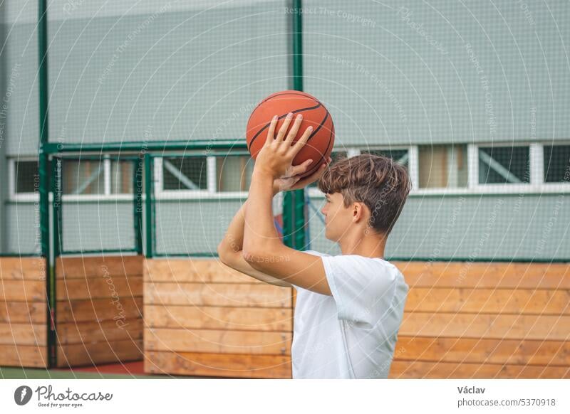 Young talented basketball player is shooting hoops on his outdoor court and training for future games and tough situations. Preparing for the season. Shooting the basket