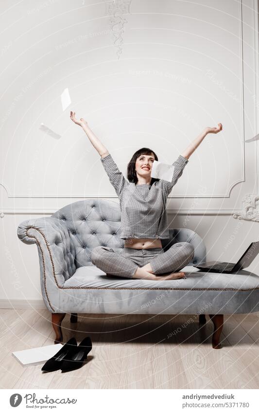 Beautiful businesswoman in gray suit is using laptop and scattering paper documents in a desire to take a break from work. High quality photo. mock up. selective focus.