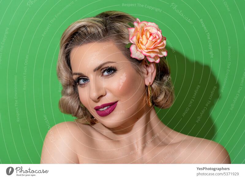 Woman portrait with a retro hairstyle isolated on a green background 40s 50s accessories beauty blonde blue color concept copy space curly cute elegant eyes