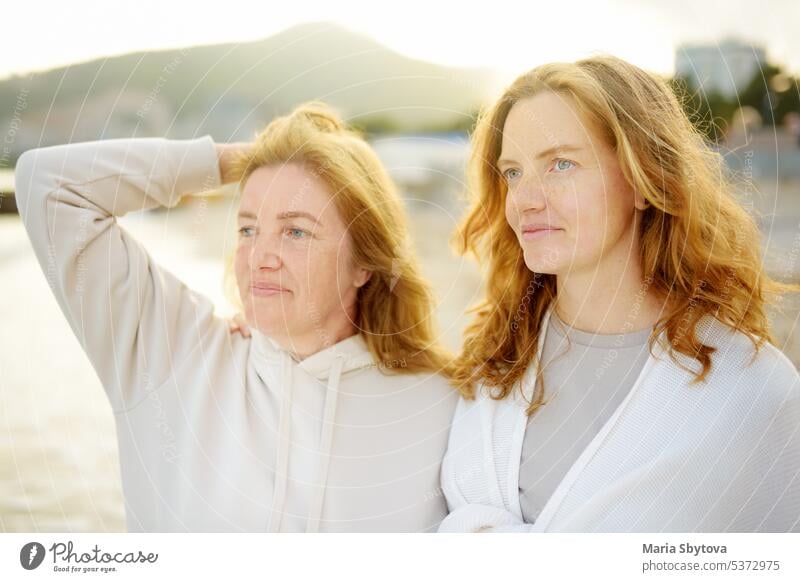 Redhead senior mother and her beautiful adult daughter are walking together and laughing family similar portrait woman redhead grown up child look alike people