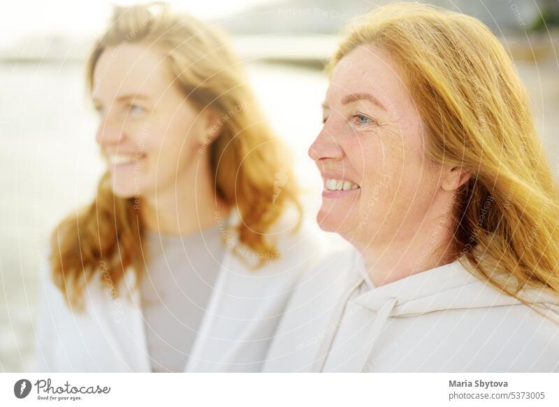 Redhead senior mother and her beautiful adult daughter are walking together and laughing family similar portrait woman redhead grown up child look alike people