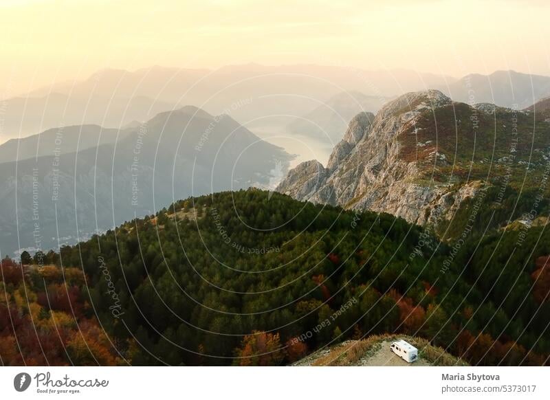 Drone aerial view of parked big modern camper motorhome on background of mountains and Boka Kotorska bay, Montenegro. Family vacation travel RV. Bicycles attached to caravan. Travel and adventure.