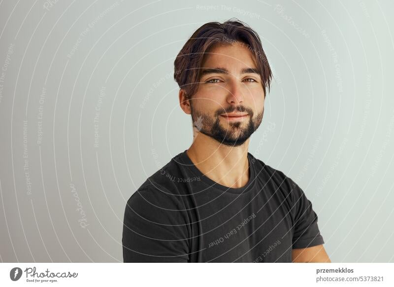 Portrait of handsome smiling young man with folded arms. Smiling joyful man with crossed hands studio shot. Isolated on gray background portrait beard headshot