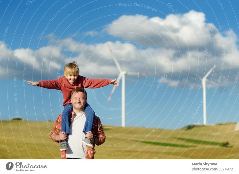 Eco activists man and child on background of power stations for renewable electric energy production. People and windmills. Wind turbines for generation electricity. Green energy