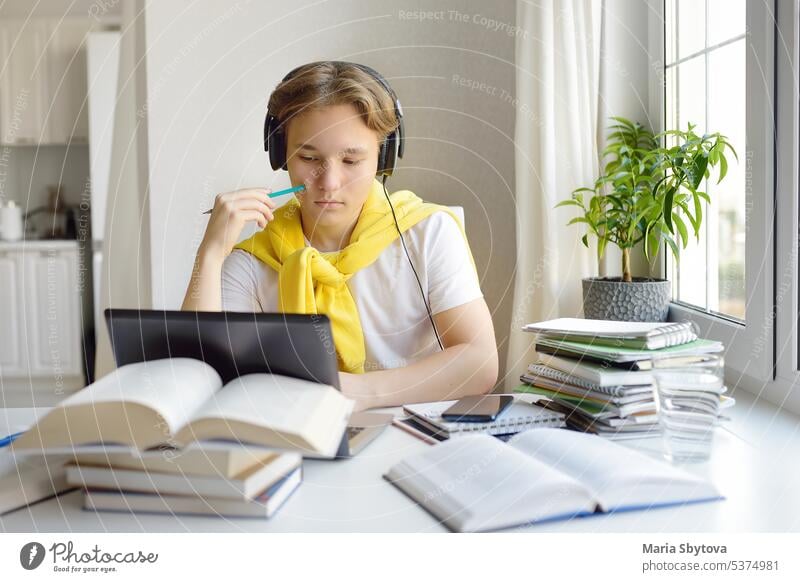 Teenager boy study at home. Online education and distance learning for children. School boy doing his physics homework using gadgets. Lessons on the internet for high school students