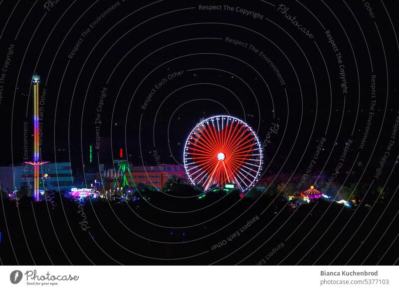 Night shot from a distance of Kiliani folk festival with Ferris wheel with heart illumination and Free Fall Tower at night Exterior shot Colour photo kiliani