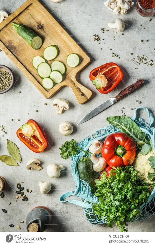 Healthy cooking with various fresh vegetables on kitchen desk with knife, cutting board and sustainable mesh bag with grocery . Top view healthy top view raw