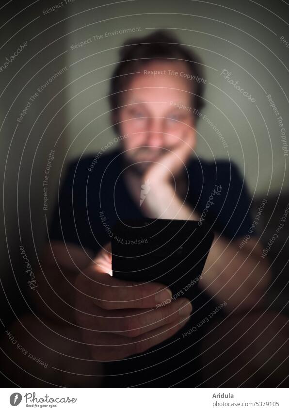 Man sitting on stairs and looking at his smartphone Cellphone hands Dark Stairs Face Facial hair Human being Eyes Facial expression Looking bored Meditative sad