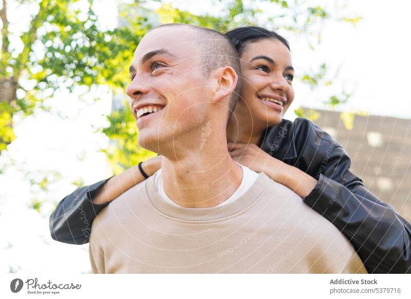 Happy couple hugging in park happy having fun piggyback ride love together relationship girlfriend boyfriend smile affection cheerful romantic joy enjoy casual