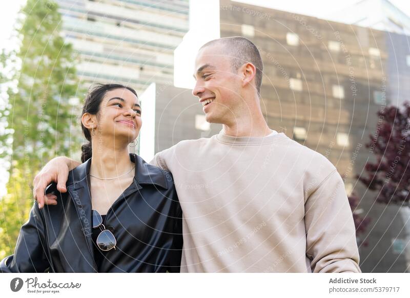 Cheerful couple embracing on street boyfriend girlfriend smile happy relationship hug embrace romantic together date city love style affection casual cheerful