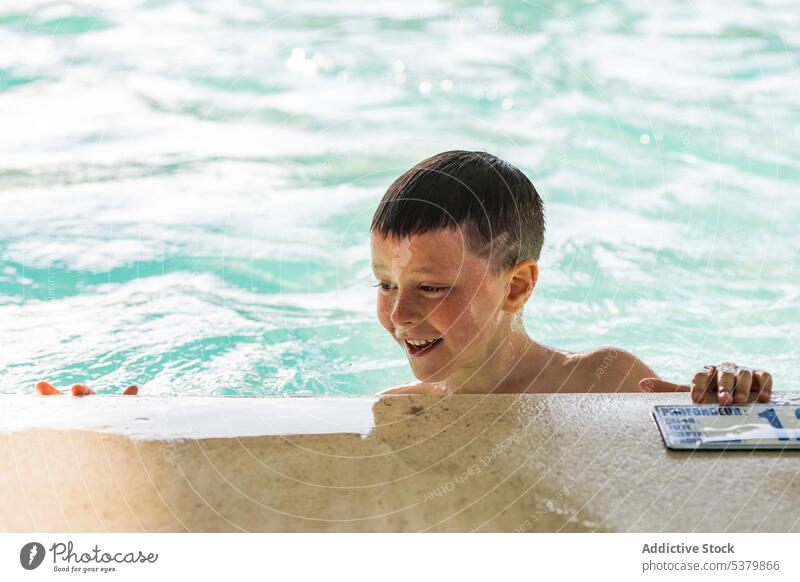 Cheerful kid swimmer with book near sea boy water smile shirtless child summer edge nature enjoy concrete childhood positive ocean daytime cheerful shore coast