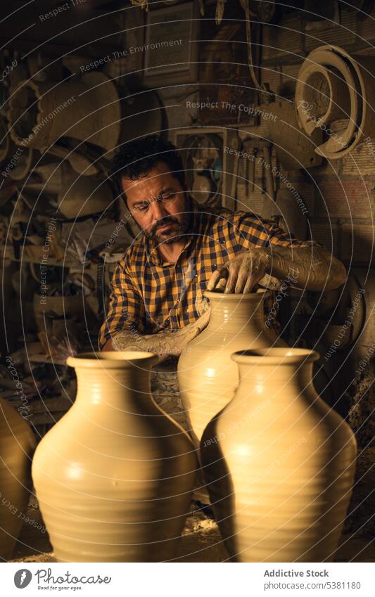 Focused man shaping vase on potters wheel in workshop pottery pottery wheel craft craftsman clay tradition artisan skill concentrate male ethnic adult beard