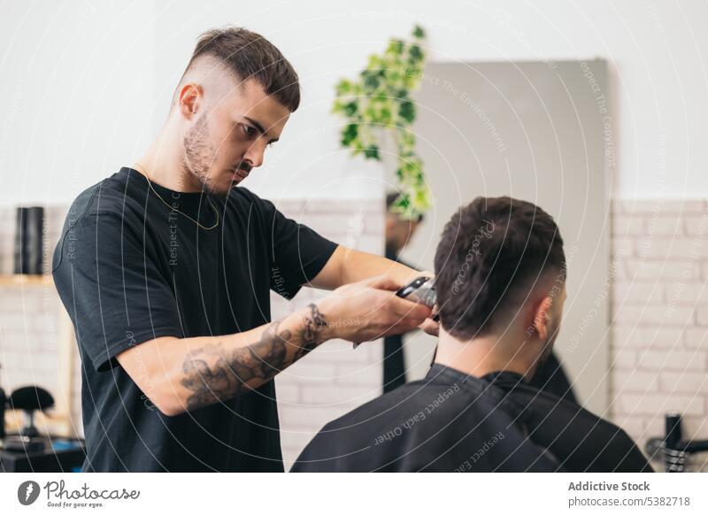 Young barber cutting hair with machine in hair salon barbershop beard bearded bearded man beauty blade care client clipping coiffure comb cutter foam guy