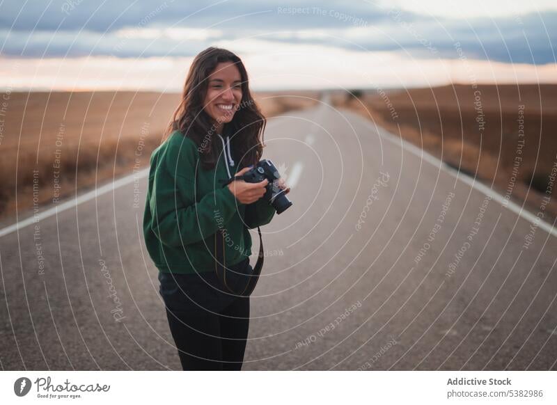 Young woman with photo camera standing on road photographer street nature smile device photography take photo positive young hobby countryside female casual