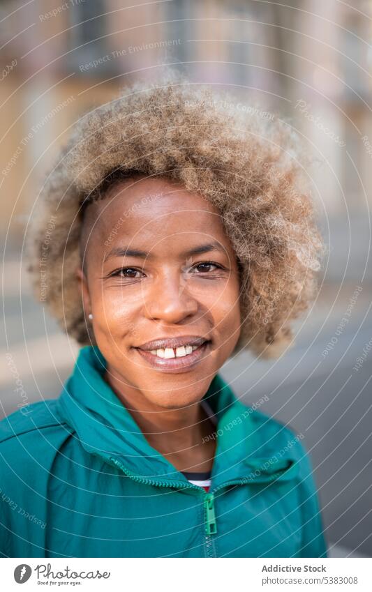 Smiling black woman with curly hair on street portrait positive cheerful happy content smile style city appearance african american ethnic afro female optimist