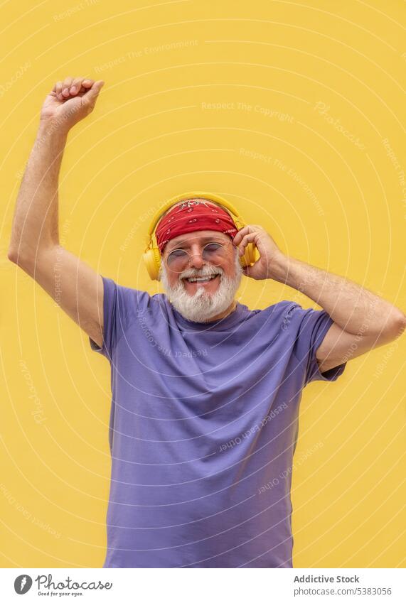 Excited man with closed eyes enjoying music over headphone excited smile dance headphones listen happy portrait senior male song casual scarf device positive