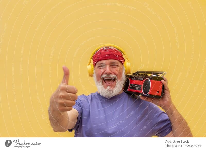 Smiling man with cassette player making thumb up sign ok like gesture vintage retro music happy headphones aged male positive senior sound smile old cheerful