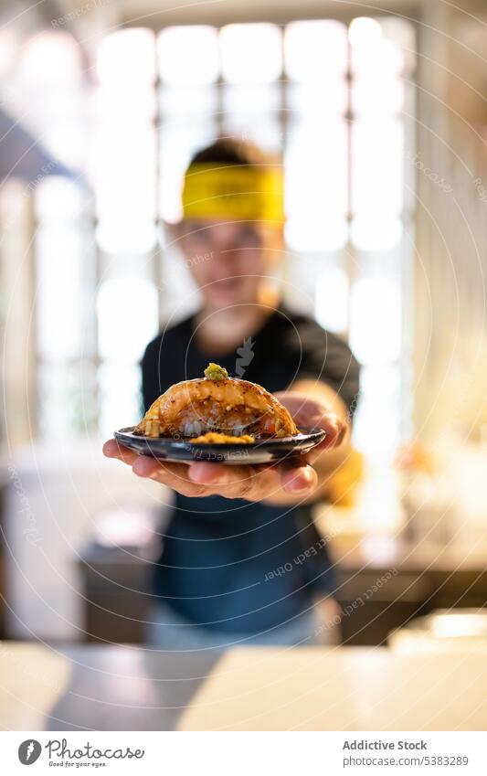 Young man with headband standing and showing nigiri sushi delicious offer food meal tasty seafood appetizing kitchen young male yummy tradition plate cuisine