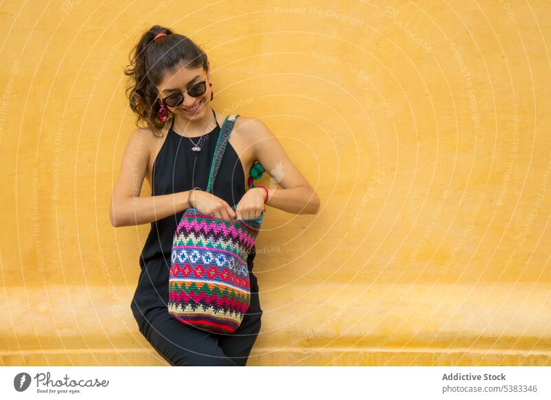 Happy young woman with bag smile happy style outfit wall knitted ornament sunglasses mexico san cristobal de las casas chiapas colorful fashion trendy cheerful