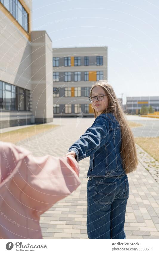 Girl holding hand of friend on pavement in city girls holding hands teenage walk bonding together positive stroll carefree teenager young summer sidewalk smile