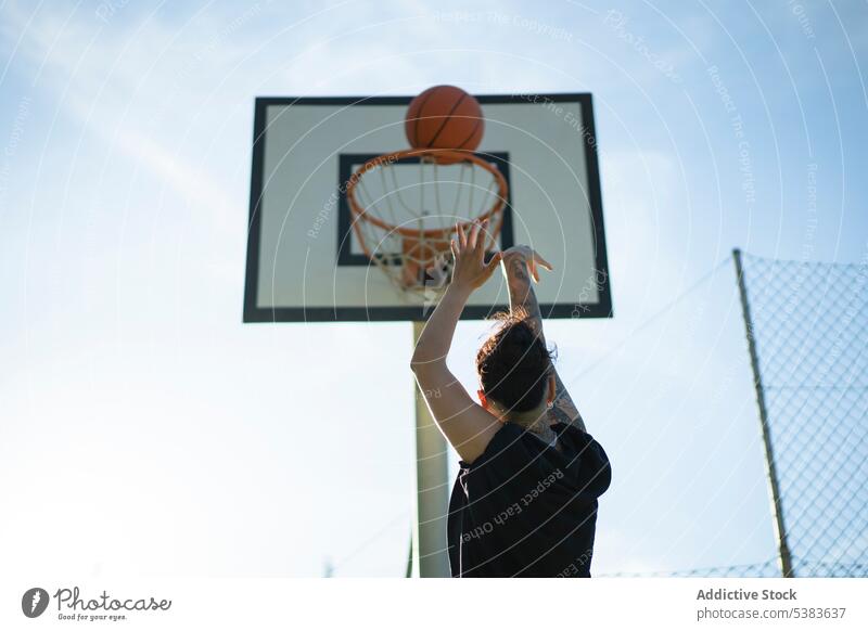 Sportswoman playing basketball on court in sunlight sportswoman unrecognizable player sports ground throw hoop billboard streetball masculine shoot training