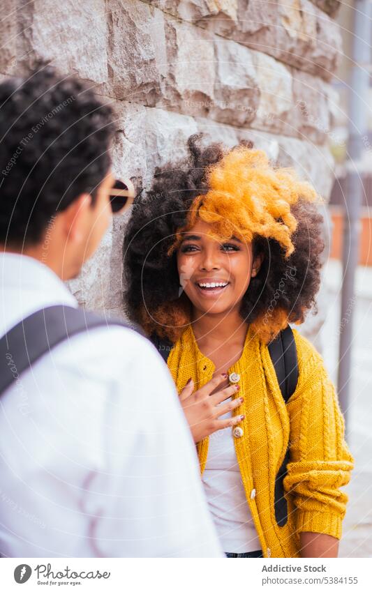 Cheerful multiethnic couple standing together on street relationship smile cheerful city wall spend time anonymous backpack positive happy young date boyfriend