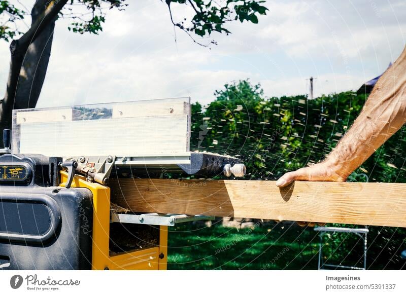 Carpenter working with electric plane on wooden beam, plank. DIY concept Joiner Men`s hand grind Wooden board Garden carpenter labour Electric plane