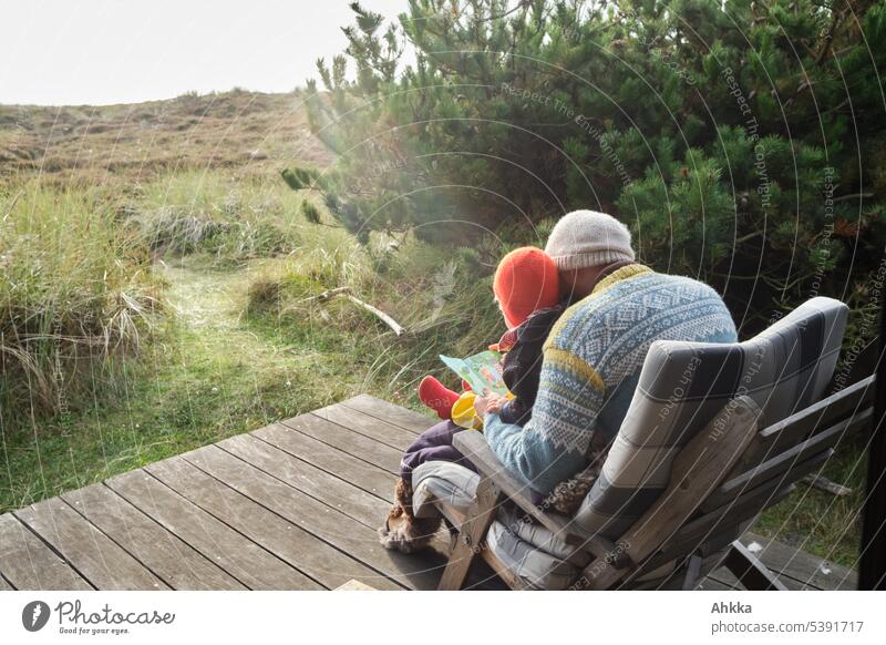 A man and a child reading a book together on a wooden porch in nature Child Father Reading Together dad spend time Infancy tell in common Happy